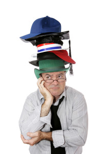 A discouraged businessman or academic wearing too many hats. Isolated on white.