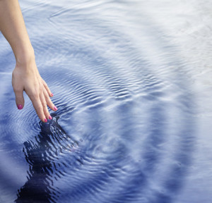 Girl touching the water with ripple effect.